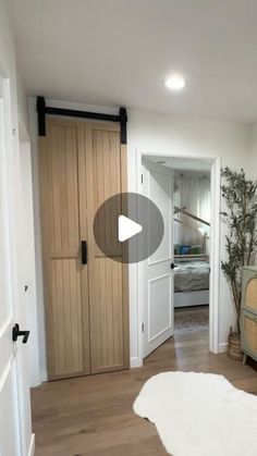 a bedroom with white walls and wood floors, an open door leading to a bed