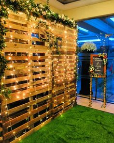 a room with artificial grass and lights on the wall, decorated with flowers and greenery