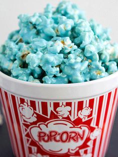 a bowl filled with blue popcorn sitting on top of a table