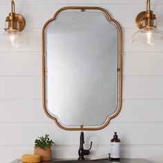 a bathroom sink with a mirror above it and two lights on the wall behind it