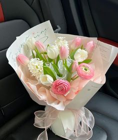 a bouquet of pink and white tulips in a car