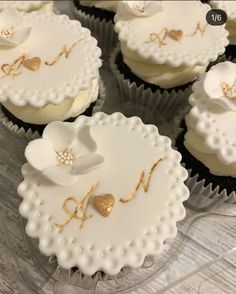 cupcakes decorated with white frosting and gold decorations on a clear platter