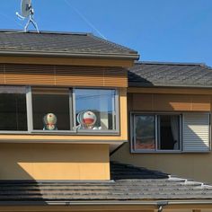 two stuffed animals are sitting in the windows of a large house on a sunny day