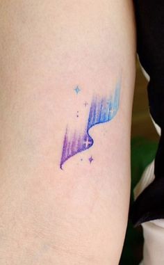 a woman's arm with a tattoo that has an image of the aurora bore on it