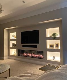 a living room with a large television mounted on the wall and built - in shelving