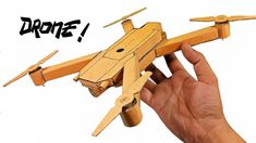 a hand holding a wooden model of a plane with the word drone written on it