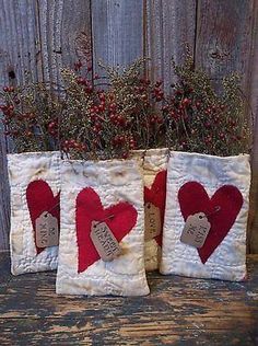 two red and white hearts are sitting on a table next to some flowers in a vase