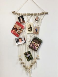 a white wall hanging with pictures and photos attached to the strings, on top of a white wall