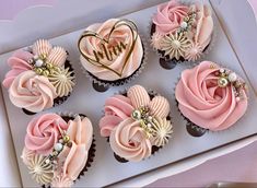 cupcakes decorated with pink and white frosting in a box