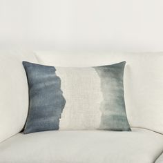 a white couch with a blue and grey pillow on it's backrests