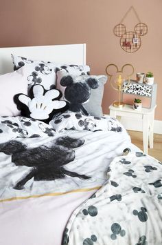 a bed with mickey mouse and minnie mouse pillow cases on it, along with two nightstands