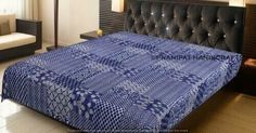 a bed with a blue blanket on top of it in a room next to a couch