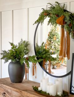 a round mirror sitting on top of a wooden shelf next to a potted plant