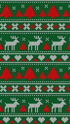 a green and red knitted christmas sweater with white deers on the front, snow - capped trees in the background