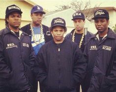 a group of young men standing next to each other in front of a white house