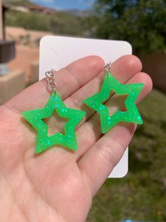 Each pair of neon green glitter star earrings are handmade to order, therefore no two pairs are identical! However, I try to get as close as possible :) Made with sterling silver fishhooks (clear rubber backing included). Hypoallergenic & nickel-free. Each star is approximately 30mm in length, and are made with resin, neon green glow in the dark powder pigment and neon green iridescent glitter. These handmade chunky neon green star earrings are glow in the dark and are uv blacklight reactive! Pe Cheap Green Star Shaped Earrings, Green Star-shaped Handmade Jewelry, Cute Green Jewelry For Party, Handmade Green Star-shaped Jewelry, Green Star-shaped Party Jewelry, Green Glitter Earrings As A Gift, Green Luminous Jewelry For Party, Luminous Green Jewelry For Party, Rave Jewelry