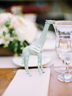 a giraffe figurine on a table next to a wine glass and napkin