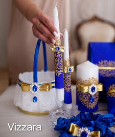 a table with blue and gold decorations on it, including candles in baskets and other items