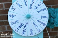 a spinning wheel with words written on it next to a blue flower and brick wall