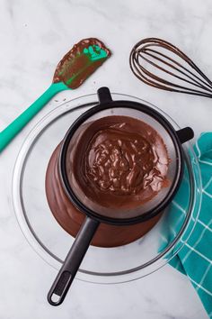 chocolate spread in a glass bowl with whisk and spoons on the side