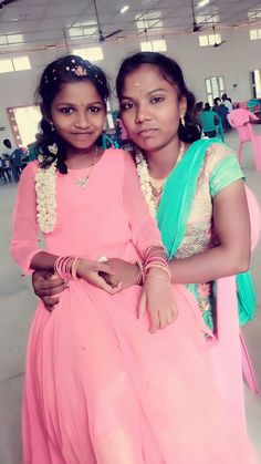 two women in pink dresses are posing for the camera with their arms around each other