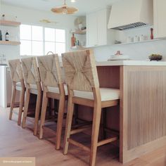 a kitchen filled with lots of counter top space and wooden chairs next to an island