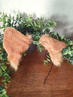 two fake bow ties on top of a wooden table next to green leaves and plants