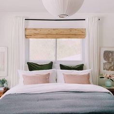 a bedroom with a large bed and two pillows on the top of it, next to a window