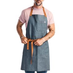 a man wearing an apron and hat with his hands in his pockets while standing against a white background