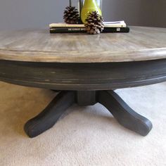 a pine cone sits on top of a round table with two books and a vase