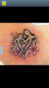 a tattoo on the back of a woman's shoulder with pink flowers and hearts