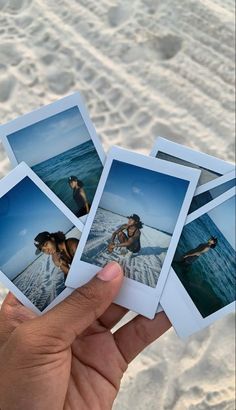 four polaroid photos being held up in front of the camera with sand and water behind them