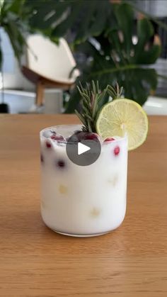 a glass filled with liquid and garnished with lemon wedges on top of a wooden table