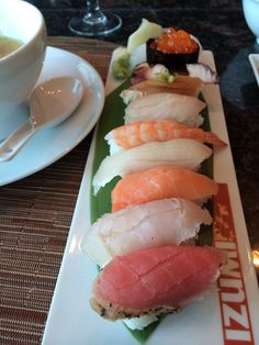 there are many different types of sushi on the plate next to a cup and saucer