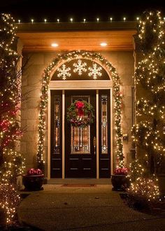 the front door is decorated with christmas lights and garlands for an elegant touch to any home