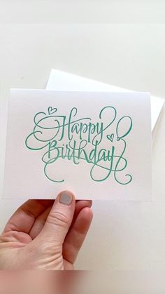 someone holding up a card with the words happy birthday written on it in green ink