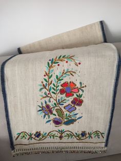 an embroidered blanket with flowers and leaves on it