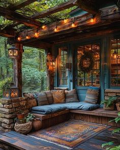 a wooden porch with lots of pillows and lights on the ceiling, surrounded by greenery