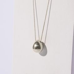 A fluid orb shaped like a seed pod hangs gracefully from an elegant chain. Perfect on its own or layered with our Pebble Charm Necklace. Sold Separately. Materials: Sterling Silver. Also available in Brass Charm: Approximately 0.75 inches in diameter by 1 inch long Chain: 18 inches, adjustable to 20 inches Our collection is made by fair wage master craftsmen in Nepal. Since each item is handmade, slight variations make each piece truly one of a kind. Metals will tarnish as they respond to moistu Unique Drop Necklace With Large Pendant, Silver Teardrop Necklace With Detachable Pendant, Elegant Orb-shaped Sterling Silver Necklace, Unique Teardrop Pendant Necklace With Polished Finish, Elegant Ball Chain Jewelry, Chemistry Jewelry, Seed Pod, Silver Age, Brass Charms