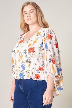 Sunkissed by primary colored floral motifs. A dream garden floral print shapes this elegant blouse with voluminous balloon sleeves and V neckline. It maintains a blouson bodice shaped by an elastic waist to create a semi peplum silhouette. Pair the look with medium washed denim and brown sandals for a casual day out.- Elastic waist- Peplum- Cropped- Lined- Color: Floral PrintSize + Fit - Model is 5'9" and wearing size 2X- Measurements taken from size 2X - Chest: 52"- Length: 24 1/2" Fabric Self: Spring V-neck Peasant Top With Blouson Sleeves, Multicolor Floral Print V-neck Peasant Top, Multicolor Tops With Gathered Balloon Sleeves, Multicolor Top With Gathered Balloon Sleeves, Multicolor Tops With Balloon Gathered Sleeves, Multicolor Balloon Sleeve Top With Gathered Sleeves, Multicolor Puff Sleeve Top With Gathered Sleeves, Multicolor Tops With Gathered Sleeves For Spring, Spring Lantern Sleeve Printed Blouse