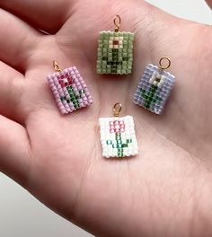 four small beaded charms in the palm of someone's hand