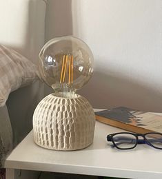 a lamp that is on top of a table next to a book and eyeglasses