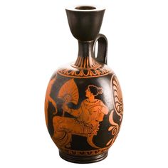 an orange and black vase is sitting on a white surface with the image of a man riding a horse