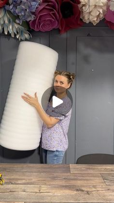 a woman standing next to a giant white vase