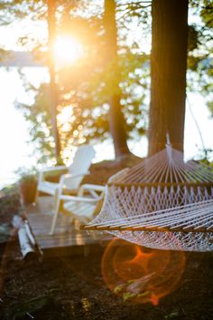 a hammock hanging from a tree in the woods with sun shining through it