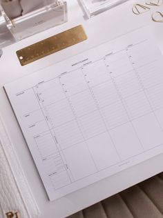 a desk with a calendar, pen and other office supplies on top of it next to a pair of glasses