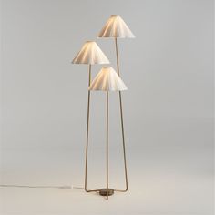 three floor lamps with white shades on them