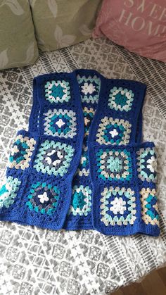 three crocheted granny afghans sitting on top of a bed next to pillows