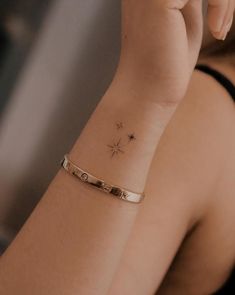 a woman wearing a gold bracelet with a star tattoo on her wrist