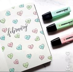 three pens sitting next to each other on top of a notepad with hearts drawn on it